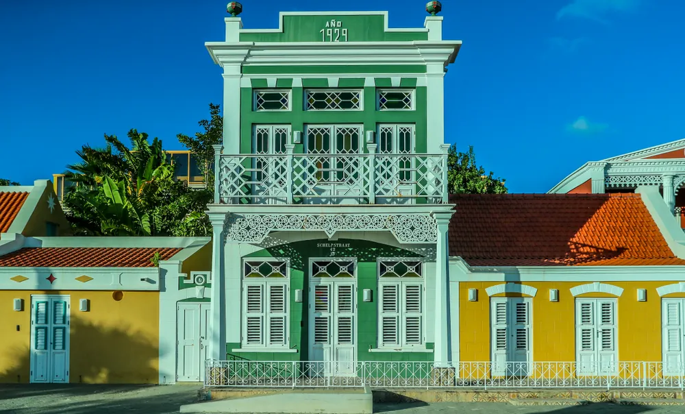 Mint-green and yellow historic facades with white shutters and balconies in Oranjestad, Aruba